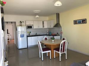 Una cocina con una mesa y un refrigerador blanco. en Departamento Mailin, en Puerto Madryn 12 fotos más
