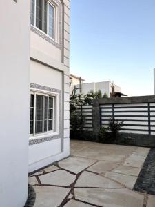 een wit gebouw met een stenen patio naast een hek bij Luxorious villa with a pool near the laguna in Dahab
