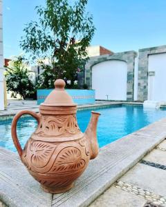 Luxorious villa with a pool near the laguna في دهب: وجود مزهرية على طاولة بجوار حمام السباحة