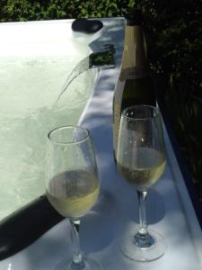 2 copas de vino blanco junto a una bañera de hidromasaje en Casa Simona Villa General Belgrano en Villa General Belgrano
