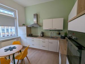 uma cozinha com armários brancos, uma mesa e um lavatório em Schönes Apartment Mitten in der Stadt III em Koblenz
