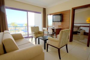 a living room with a couch and chairs and a television at Le Monde Beach Resort & Spa in İzmir