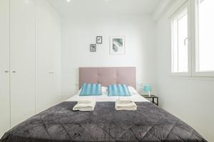 a white bedroom with a large bed with blue pillows at Modern, Stylish Apartment with balcony in Valencia