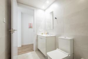 a white bathroom with a toilet and a sink at Modern, Stylish Apartment with balcony in Valencia
