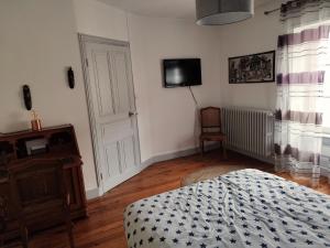 a bedroom with a bed and a tv on the wall at Chaleureuse maison de ville à côté de la mairie ronde in Ambert