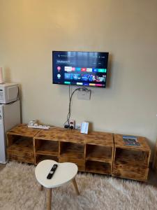 a living room with a wooden entertainment center with a tv on the wall at Ruby Modern Homes Studio-Imara Daima,Behind Imaara Mall-JKIA-Horizon in Nairobi