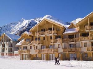 Un homme fait du ski en face d'un lodge de ski dans l'établissement Centre station 1800 - 2 Chambres - Vue panoramique, aux Orres