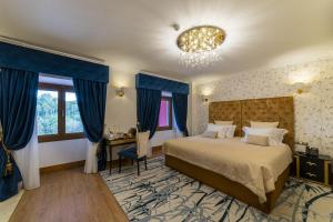 sypialnia z łóżkiem z niebieskimi zasłonami i żyrandolem w obiekcie Sintra Marmòris Camélia w mieście Sintra