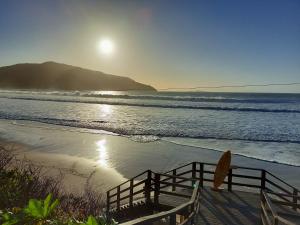 un banco en una playa con el sol saliendo sobre el océano en Casa agradável nos Açores com piscina para até 13 pessoas com 4 suites, en Florianópolis