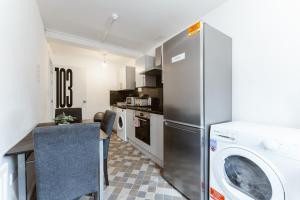 a kitchen with a refrigerator and a table with a washing machine at Whitechapel en-suite beds to stay in London