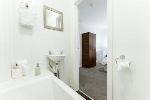 a white bathroom with a sink and a mirror at Whitechapel en-suite beds to stay in London