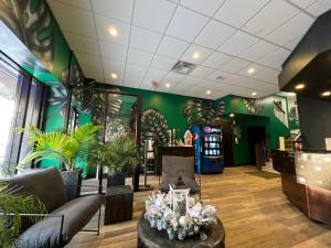 a lobby with green walls and furniture and plants at Commercial Hotel in Edmonton