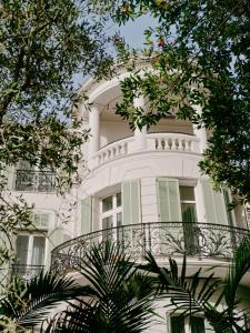 a white building with a balcony and trees at Hôtel & Spa Belle Plage in Cannes
