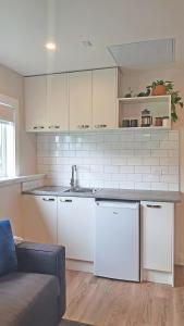a kitchen with white appliances and a couch in a room at Retro on Queen, Papakura in Papakura