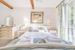 a white bedroom with a large bed and a window at Briardene Cottage - A Superb Bijou Retreat with Jacuzzi near an Excellent Village Pub in Yelverton