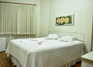 1 dormitorio con 1 cama grande con manta blanca en Hotel Monet, en Erechim