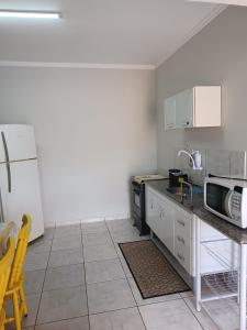 eine Küche mit einer Spüle und einer Mikrowelle in der Unterkunft Residencial Joed 2 in Dourados
