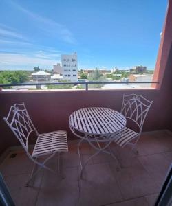 2 sillas y mesa en un balcón con vistas en Estudio bello y tranquilo en Cipolletti