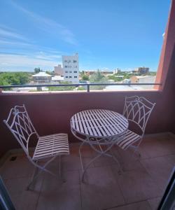 una mesa y sillas en un balcón con vistas en Estudio bello y tranquilo en Cipolletti