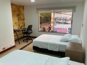 1 Schlafzimmer mit 2 Betten, einem Schreibtisch und einem Fenster in der Unterkunft Departamento Cerca a la Terminal del Sur MAG201 in Medellín