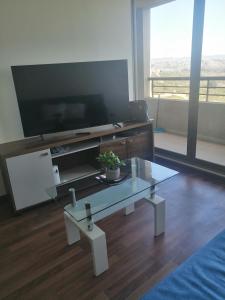 a living room with a glass table and a tv at Altavistamar in Viña del Mar