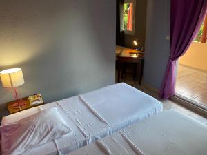 a bedroom with two beds and a table and a window at Hotel La Chaumiere in Matoury