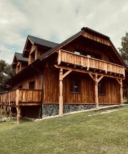 a large wooden house with a grass yard at Marzeniówka in Lutowiska