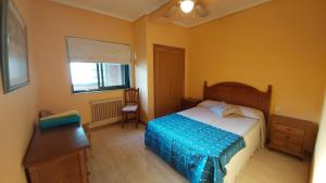 een slaapkamer met een bed, een bureau en een raam bij Apartamento Samil Primera Línea de Playa 2M in Vigo
