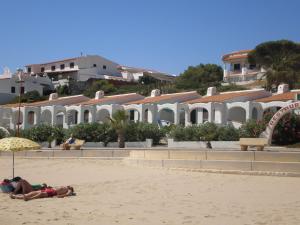 a couple of people laying on the sand on the beach at Hotel Llorca in Platja de l’Almadrava