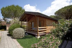 una piccola cabina in legno in un giardino fiorito di Camping Village Oasi ad Albinia