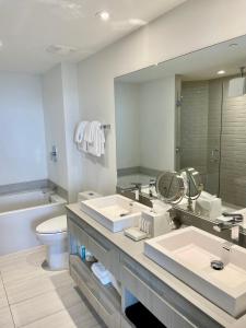 a bathroom with two sinks and a toilet and a mirror at Hyde Beach House Lux Apartment in Hollywood