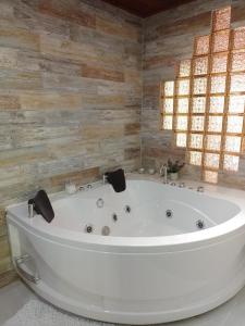 baño con bañera blanca grande y paredes de madera. en Hotel Colonial Andino - Parque principal de Pitalito, en Pitalito