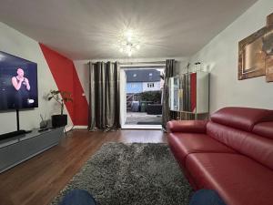 a living room with a red couch and a tv at Sensational 3-Bed Home Near Bluewater in Kent