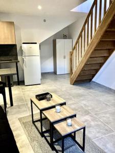 een keuken met 2 tafels, een koelkast en een trap bij Duplex au coeur du village in Les Mées