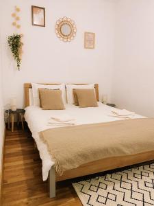 1 dormitorio con 1 cama grande con sábanas y almohadas blancas en Cozy 2-Bedroom Boho-Themed Home, en Caransebeş