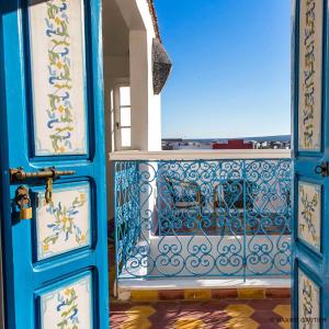 a blue door with a balcony with a view at Hôtel Emeraude Essaouira in Essaouira