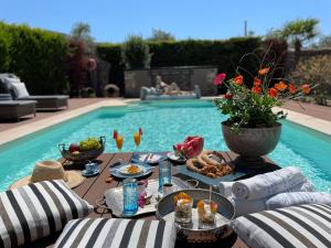 una mesa con comida y bebida junto a una piscina en Byblos Luxury Villa en Prinos