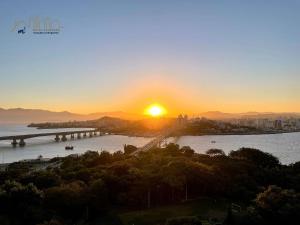 zachód słońca nad rzeką z mostem i miastem w obiekcie Central Park Flat Residence - Home Time w mieście Florianópolis
