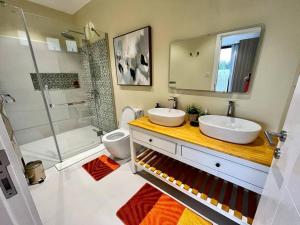 La salle de bains est pourvue de 2 lavabos, d'une douche et de toilettes. dans l'établissement Rich villa is new, stunning and modern, à Calodyne