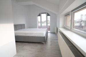 ein weißes Schlafzimmer mit einem Bett und zwei Fenstern in der Unterkunft Bright and cozy apartment nr. 5 in Chişinău