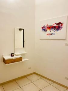 ein weißes Zimmer mit einem Spiegel und einem Bild an der Wand in der Unterkunft Napoli Forcella House al centro di Napoli in Neapel
