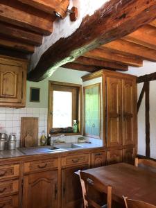 cocina con armarios de madera, mesa y ventana en Longère les pieds dans l eau, en Saint-Philbert-sur-Risle