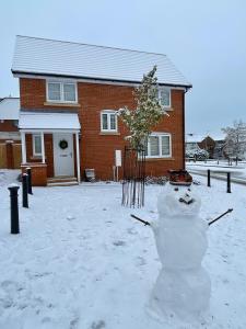 a snowman in front of a house in the snow at Aspen Villa in Hemel Hempstead