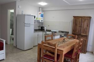 cocina con mesa de madera y nevera blanca en Piscis I en Córdoba