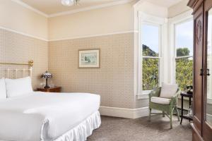 a bedroom with a bed and a window and a chair at Centrella Hotel, a Kirkwood Collection Hotel in Pacific Grove