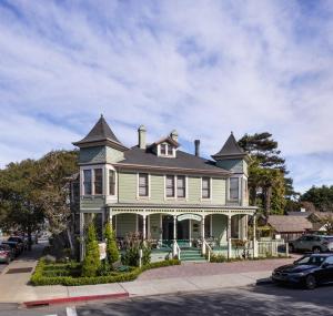 ein großes grünes Haus mit einem Turm auf einer Straße in der Unterkunft Centrella Hotel, a Kirkwood Collection Hotel in Pacific Grove