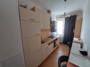 eine kleine Küche mit weißen Schränken und einem Tisch in der Unterkunft Apartmán Merry (9) in Bratislava