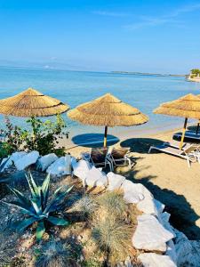 a beach with umbrellas and chairs and the ocean at Byblos Aria-The Sea Side Luxury Villa in Skala Sotiros