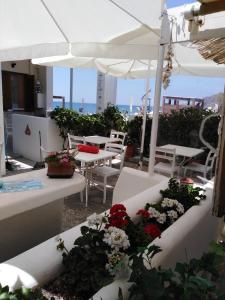 a patio with white tables and chairs and flowers at Marilena in Skala Eresou