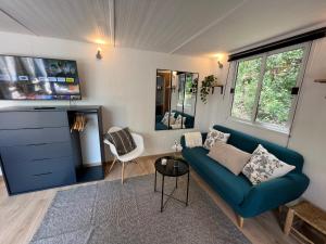 uma sala de estar com um sofá azul e uma televisão em Superbe Cabane JACUZZI JARDIN CLIM WIFI PARKING em Meyreuil